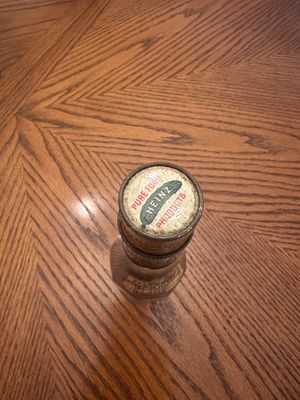 Sale Photo Thumbnail #64: Vintage Heinz Pure Food Products glass bottle featuring a branded metal cap with a pickle graphic and age-related patina.