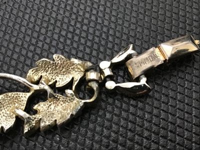 Sale Photo Thumbnail #81: Vintage costume jewelry bracelet by Emmons. Features white painted or enameled metal leaf links interspersed with light green molded glass cabochons set with small clear rhinestones. Signed EMMONS on the foldover clasp. Measures approximately 7 inches in 