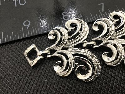 Sale Photo Thumbnail #21: A vintage silver-tone costume jewelry link bracelet featuring ornate scroll/swirl filigree-style links with textured detailing. Measures approximately 7.5 inches in length with a fold-over clasp. Good condition with light vintage wear.
