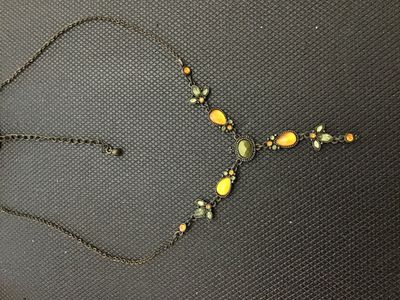 Sale Photo Thumbnail #198: An antiqued bronze-tone Y-drop necklace featuring faceted green, amber-yellow teardrop cabochons, and small accent rhinestones with leafy floral links. Includes an adjustable extender chain. In good pre-owned condition with no missing stones visible.