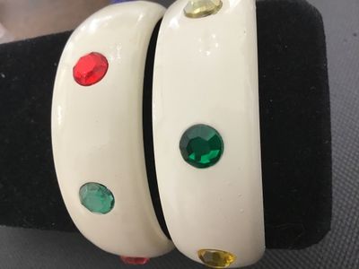 Sale Photo Thumbnail #4: Pair of cream/off-white plastic or lucite thick bangle bracelets studded with round faceted multi-colored rhinestones (red, blue, green, purple, yellow). Each bangle measures approximately 2.5 inches in inner diameter. Both bracelets are in good vintage c