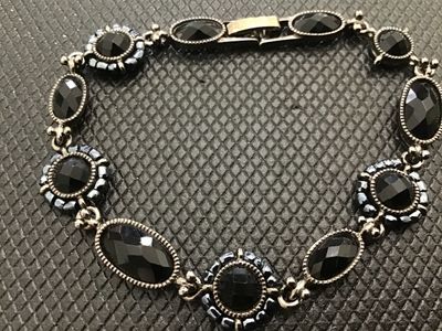 Sale Photo Thumbnail #186: A Liz Claiborne vintage costume jewelry link bracelet featuring dark silvertone metal set with faceted black stones and beaded halo accents. Includes a fold-over clasp marked 'LC'. Good condition with light vintage surface wear.