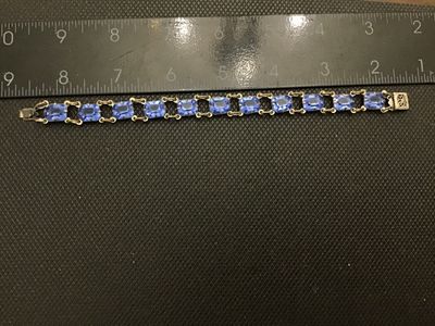 Sale Photo Thumbnail #207: Vintage costume jewelry link bracelet featuring emerald-cut light blue glass stones set in open-backed claw prongs. Includes a decorative filigree push-in box clasp with safety tongue. Measures approximately 7.25 inches in overall length. Metal shows surf