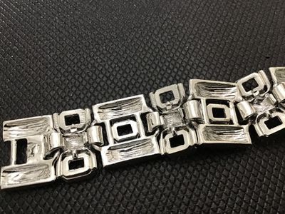 Sale Photo Thumbnail #179: A vintage silver-tone wide link panel bracelet featuring a textured bark-like finish and geometric rectangular cut-out links. Features a fold-over clasp closure. Measures approximately 7.5 inches long. Shows minor vintage wear consistent with age, but ove