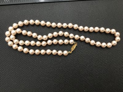 Sale Photo Thumbnail #159: Single strand pearl necklace featuring cream/pinkish tone beads and a gold-tone filigree fishhook clasp. Individually knotted between pearls. Appears to be vintage. Shows light wear consistent with age, with minor oxidation near the clasp connection point