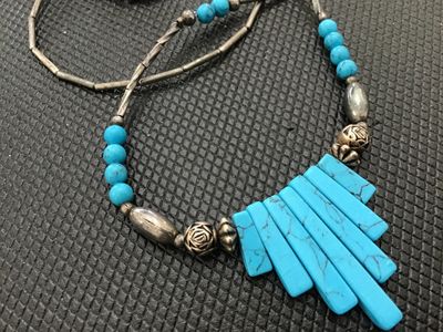 Sale Photo Thumbnail #161: Southwestern style beaded necklace featuring turquoise-colored fan-shaped pendant slabs and round beads, accented with silver-tone liquid beads, twisted bar spacers, and patterned accent beads. Finished with a lobster claw clasp. Good condition with light