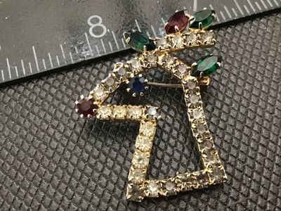 Sale Photo Thumbnail #113: Vintage gold-tone rhinestone brooch shaped like a Christmas bell topped with holly and berries. Features clear round rhinestones outlining the bell frame with red, green, and blue rhinestone accents. Pin rollover clasp on back. Measures approximately 1.5 
