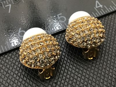 Sale Photo Thumbnail #39: Pair of designer vintage Blair Delmonico clip-on earrings. Features a textured gold-tone setting pave-set with sparkling clear rhinestones, accented with a smooth white cabochon top. Both clips are signed 'Blair Delmonico' on the back plaque. Good pre-own