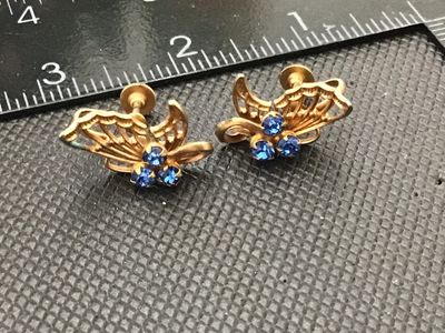 Sale Photo Thumbnail #102: Pair of vintage gold-tone screw-back earrings featuring an openwork butterfly design accented with three round blue rhinestones. Each earring measures approximately 3/4 inches long. Shows minor wear and patina consistent with age.