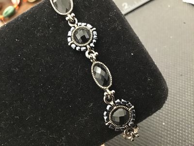 Sale Photo Thumbnail #184: A Liz Claiborne vintage costume jewelry link bracelet featuring dark silvertone metal set with faceted black stones and beaded halo accents. Includes a fold-over clasp marked 'LC'. Good condition with light vintage surface wear.
