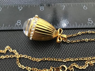 Sale Photo Thumbnail #8: A Joan Rivers Classics quartz pendant watch designed in an acorn shape with clear rhinestone accents around the bezel and a bow-shaped bail. Features a gold-tone sunburst dial with rhinestone hour markers and a matching gold-tone chain. Includes the origi