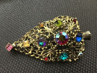 Sale Photo Thumbnail #127: A vintage gold-tone filigree Christmas tree brooch pin by DODDZ. It features multi-colored rhinestones and aurora borealis accents in various cuts and settings. Signed ©DODDZ on the reverse with a rollover pin clasp. Measures approximately 2.5 inches in 