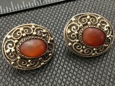 Sale Photo Thumbnail #76: Pair of vintage oval screw-back earrings featuring intricate silver wire filigree and beaded granulation work centered with polished reddish-orange carnelian cabochons. Show classic age patina with intact screw backs. Each measures approximately 3/4 inch 