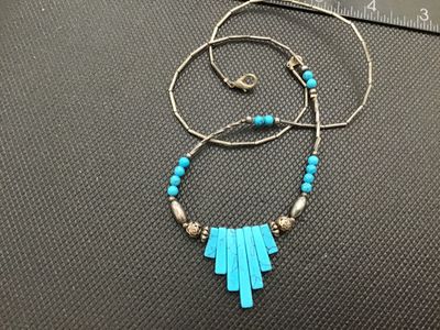 Sale Photo Thumbnail #160: Southwestern style beaded necklace featuring turquoise-colored fan-shaped pendant slabs and round beads, accented with silver-tone liquid beads, twisted bar spacers, and patterned accent beads. Finished with a lobster claw clasp. Good condition with light