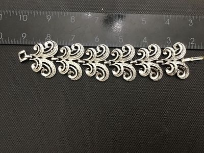 Sale Photo Thumbnail #20: A vintage silver-tone costume jewelry link bracelet featuring ornate scroll/swirl filigree-style links with textured detailing. Measures approximately 7.5 inches in length with a fold-over clasp. Good condition with light vintage wear.