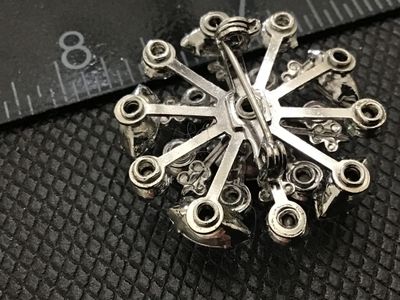 Sale Photo Thumbnail #111: Vintage silver-tone metal starburst brooch featuring multi-tiered clear glass rhinestones in round and marquise cuts. Measures approximately 1.5 inches in diameter. Features a secure rollover safety clasp on the back. Unmarked. In good vintage condition w
