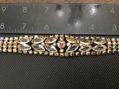 Sale Photo Thumbnail #54: A vintage gold-tone costume jewelry bracelet featuring clear marquise-cut rhinestones flanked by iridescent aurora borealis accent crystals. Features a fold-over clasp closure. Measures approximately 7 inches long. Good vintage condition with light surfac