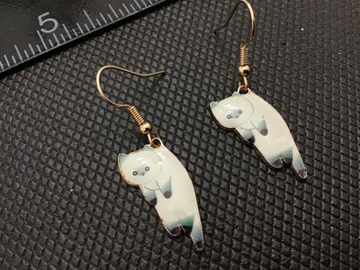 Sale Photo Thumbnail #209: Pair of gold-tone dangle fishhook earrings featuring enamelled white and dark point Siamese cat charms. Good condition with light surface wear.