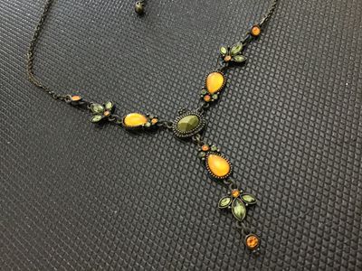 Sale Photo Thumbnail #197: An antiqued bronze-tone Y-drop necklace featuring faceted green, amber-yellow teardrop cabochons, and small accent rhinestones with leafy floral links. Includes an adjustable extender chain. In good pre-owned condition with no missing stones visible.