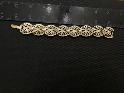 Sale Photo Thumbnail #17: A vintage Coro gold-tone costume jewelry panel link bracelet featuring openwork leaf motif design with textured and polished details. Signed 'Coro' on the fold-over clasp closure. Measures approximately 7 inches in length. In good vintage condition with m