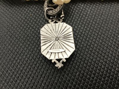 Sale Photo Thumbnail #14: Avon costume jewelry necklace featuring multi-strand white faux rice pearls, a toggle clasp, and an Art Deco style silvertone pendant set with mother of pearl style face and clear rhinestone accent. Stamped ©AVON on the back of the pendant. Measures appr