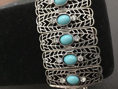 Sale Photo Thumbnail #182: Silver-tone filigree metal stretch bracelet featuring oval turquoise-colored cabochons flanked by clear rhinestones. Features articulated, lattice-style panels strung on elastic cords. Good pre-owned condition with light wear.