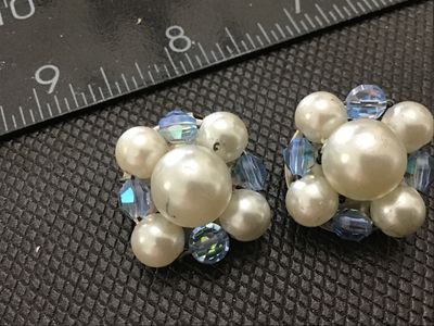 Sale Photo Thumbnail #131: A pair of vintage clip-on cluster earrings featuring faux pearls and faceted light blue aurora borealis crystal beads wired onto a perforated metal base. 

- Condition: Good vintage condition with some light wear to the faux pearl coating and slight tarni