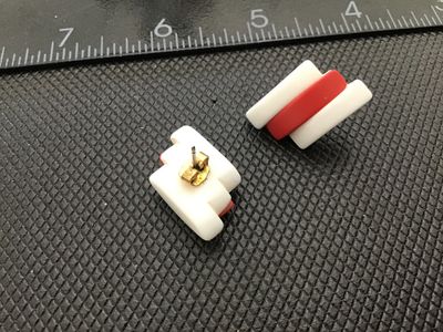 Sale Photo Thumbnail #32: Pair of vintage retro-style pierced post earrings featuring a bold diagonal striped design in opaque white and red plastic or resin. Measure approximately 1 inch in length based on ruler scale shown. Good vintage condition with post backs attached.
