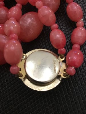 Sale Photo Thumbnail #225: A vintage double-strand beaded necklace featuring salmon pink molded plastic oval and round beads with smaller spacer beads. Includes a gold-tone push-in box clasp with a matching cabochon accent, marked 'HONG KONG' on the reverse. In good vintage conditi