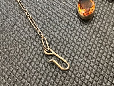 Sale Photo Thumbnail #85: Vintage or antique-style choker necklace featuring intricate metal filigree teardrop charms alternating with bezel-set faceted oval amber/topaz-colored glass stones. Connected on a paperclip-link chain with a hook clasp. Metal shows light tarnishing and p