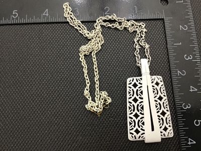Sale Photo Thumbnail #91: A vintage mid-century style white enamel pendant necklace featuring an openwork, filigree geometric lattice pattern with a sleek modern overlay accent. Suspended from a matching white enamelled link chain with a gold-tone spring ring clasp. 

- Pendant Di