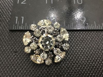 Sale Photo Thumbnail #112: Vintage silver-tone metal starburst brooch featuring multi-tiered clear glass rhinestones in round and marquise cuts. Measures approximately 1.5 inches in diameter. Features a secure rollover safety clasp on the back. Unmarked. In good vintage condition w