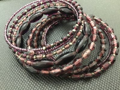 Sale Photo Thumbnail #168: Multi-strand memory wire wrap bracelet featuring an assortment of purple and plum glass beads in faceted, oval, and seed bead shapes with spacer accents. Flexible cuff design easily adjusts to fit most wrists. In good pre-owned condition with minor signs 