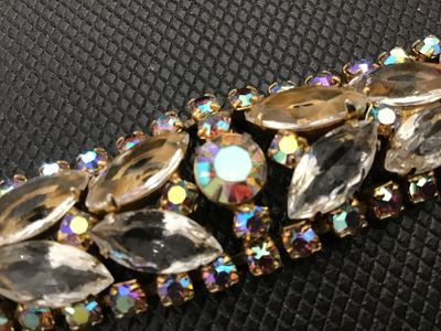 Sale Photo Thumbnail #58: A vintage gold-tone costume jewelry bracelet featuring clear marquise-cut rhinestones flanked by iridescent aurora borealis accent crystals. Features a fold-over clasp closure. Measures approximately 7 inches long. Good vintage condition with light surfac