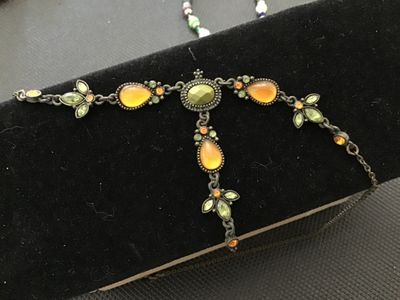Sale Photo Thumbnail #196: An antiqued bronze-tone Y-drop necklace featuring faceted green, amber-yellow teardrop cabochons, and small accent rhinestones with leafy floral links. Includes an adjustable extender chain. In good pre-owned condition with no missing stones visible.
