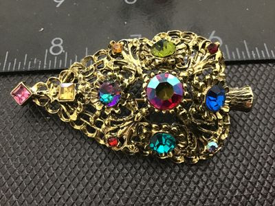 Sale Photo Thumbnail #129: A vintage gold-tone filigree Christmas tree brooch pin by DODDZ. It features multi-colored rhinestones and aurora borealis accents in various cuts and settings. Signed ©DODDZ on the reverse with a rollover pin clasp. Measures approximately 2.5 inches in 