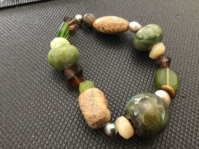 Sale Photo Thumbnail #143: An artisan beaded stretch bracelet featuring an eclectic mix of earth-toned elements, including green jade-like stones, picture jasper, iridescent pearls, faceted glass, and glazed ceramic beads. In good pre-owned condition with no visible damage.