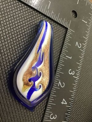 Sale Photo Thumbnail #219: Handmade art glass pendant featuring swirls of cobalt blue, opaque white, and gold aventurine glitter encased in clear glass. Measures approximately 2.5 inches in length by 1.25 inches in width. Includes an integrated glass loop at the top for hanging on 