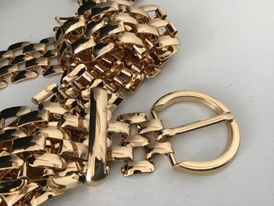 Sale Photo Thumbnail #135: A stylish gold-tone metal mesh link chain belt featuring an interlocking grid pattern and a circular buckle closure. Features a drop tail design. Appears in good pre-owned condition with bright finish and minimal light surface wear.