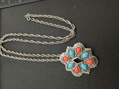 Sale Photo Thumbnail #231: A vintage Avon silver-tone convertible pendant brooch necklace featuring a Southwestern style starburst medallion set with faux turquoise, coral-colored, and black resin stones. The versatile piece functions as both a pendant on a twisted rope chain and a
