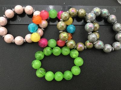 Sale Photo Thumbnail #10: Lot of 5 beaded stretch bracelets featuring oversized round beads in various colors, including pearlescent pink, iridescent olive green, iridescent gray, bright green, and a multi-color marbled style. Most bracelets include small decorative silver-tone sp