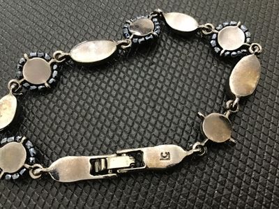 Sale Photo Thumbnail #185: A Liz Claiborne vintage costume jewelry link bracelet featuring dark silvertone metal set with faceted black stones and beaded halo accents. Includes a fold-over clasp marked 'LC'. Good condition with light vintage surface wear.