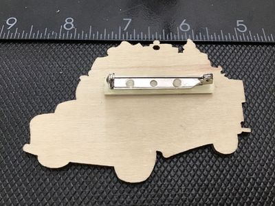 Sale Photo Thumbnail #118: Wooden brooch pin featuring a printed watercolor-style graphic of a green vintage pickup truck loaded with Christmas gifts, a tree, and holiday decor. Decorated with a small rhinestone accent at the top. Measures approximately 3 inches wide. Good pre-owne