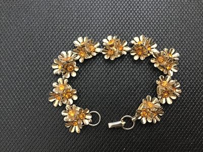 Sale Photo Thumbnail #174: Vintage Coro gold-tone bracelet featuring multi-petal floral links set with amber or topaz-colored rhinestones. Includes a fold-over clasp marked "Coro". Light vintage wear consistent with age, overall good condition with all stones present.