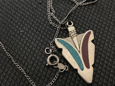 Sale Photo Thumbnail #23: Sterling silver chain necklace featuring an arrowhead-shaped pendant with crushed stone or resin inlay in turquoise blue and reddish-brown. The spring ring clasp and hang tag are stamped 'STERLING' and 'SWEET'. 

- Pendant Dimensions: Approx. 1.25 inches 
