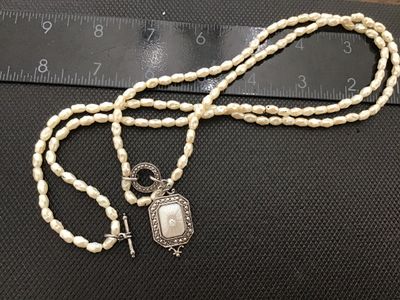 Sale Photo Thumbnail #15: Avon costume jewelry necklace featuring multi-strand white faux rice pearls, a toggle clasp, and an Art Deco style silvertone pendant set with mother of pearl style face and clear rhinestone accent. Stamped ©AVON on the back of the pendant. Measures appr