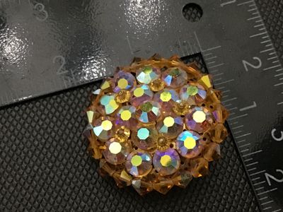 Sale Photo Thumbnail #237: Vintage round domed cluster brooch set with iridescent aurora borealis rhinestones and amber/topaz-colored faceted crystal beads. Features a textured silver-tone backing with a locking pin clasp. Measures approximately 1.5 inches in diameter. In good vint