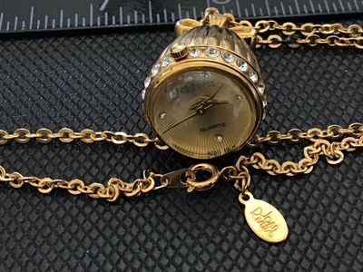 Sale Photo Thumbnail #7: A Joan Rivers Classics quartz pendant watch designed in an acorn shape with clear rhinestone accents around the bezel and a bow-shaped bail. Features a gold-tone sunburst dial with rhinestone hour markers and a matching gold-tone chain. Includes the origi