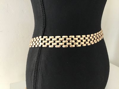Sale Photo Thumbnail #134: A stylish gold-tone metal mesh link chain belt featuring an interlocking grid pattern and a circular buckle closure. Features a drop tail design. Appears in good pre-owned condition with bright finish and minimal light surface wear.