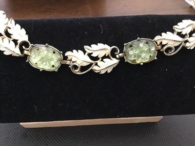 Sale Photo Thumbnail #80: Vintage costume jewelry bracelet by Emmons. Features white painted or enameled metal leaf links interspersed with light green molded glass cabochons set with small clear rhinestones. Signed EMMONS on the foldover clasp. Measures approximately 7 inches in 